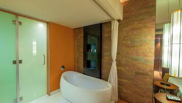 Un baño moderno con una bañera independiente, cabina de ducha con paredes de vidrio y tocador de madera con espejo.