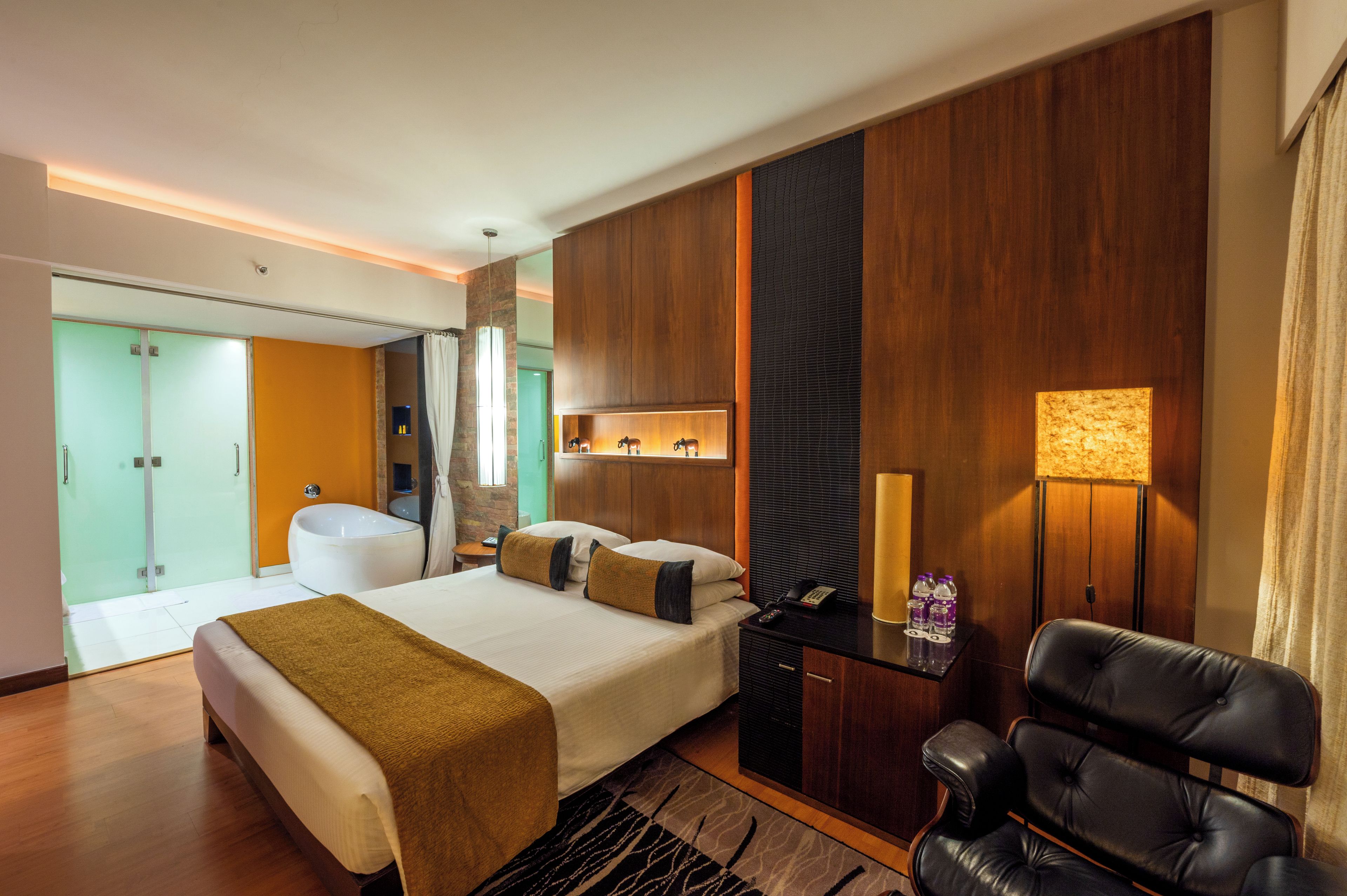 A modern hotel room with a large bed, a desk, a chair, a bathroom, and a view of the city.