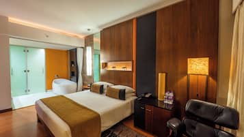 A modern hotel room with a large bed, a desk, a chair, a bathroom, and a view of the city.