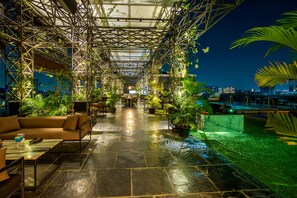 A rooftop lounge with a glass ceiling, seating areas, and potted plants. - O Hotel Pune (Pune)