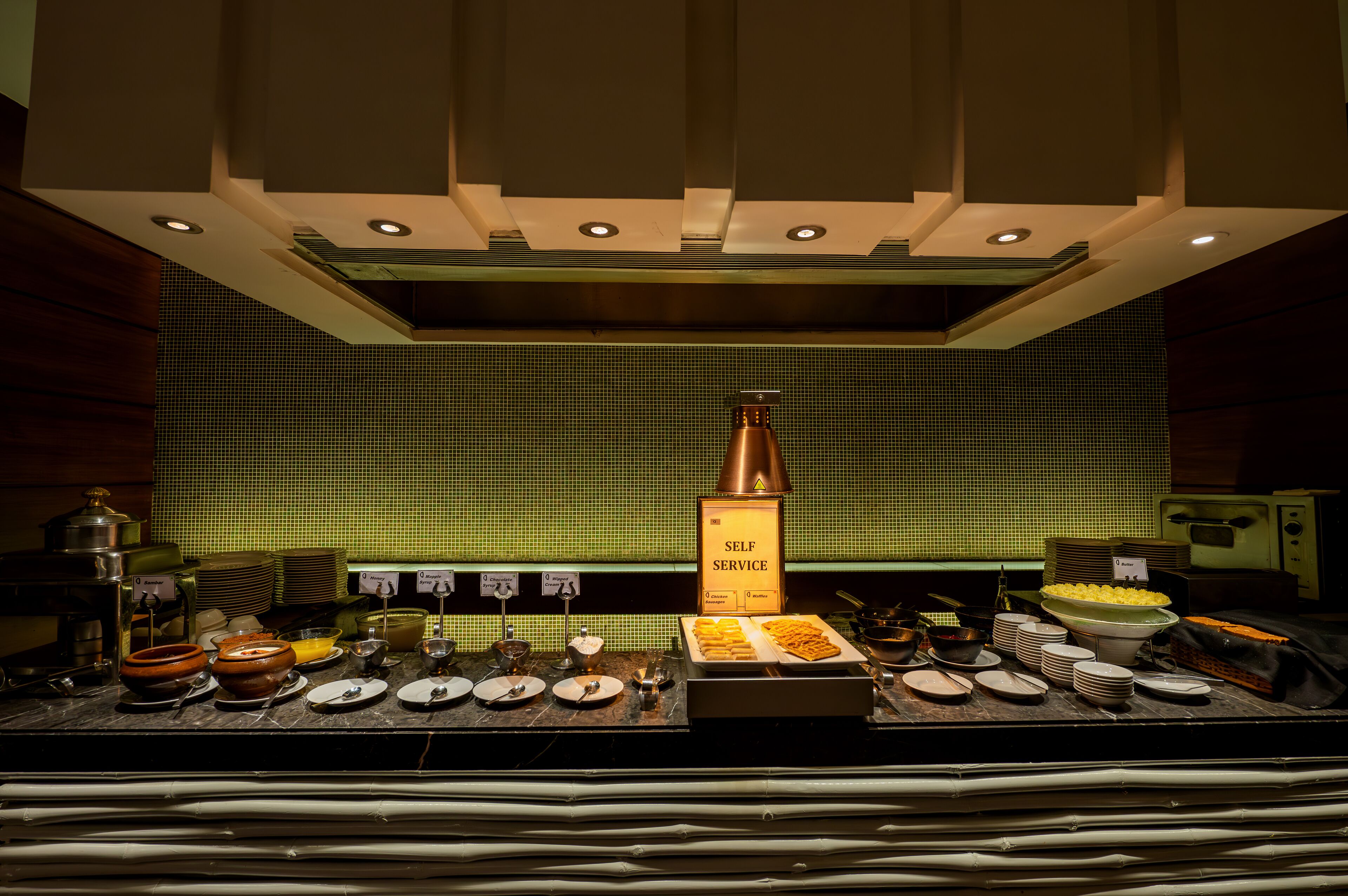 A self-service breakfast buffet with various food items and utensils.