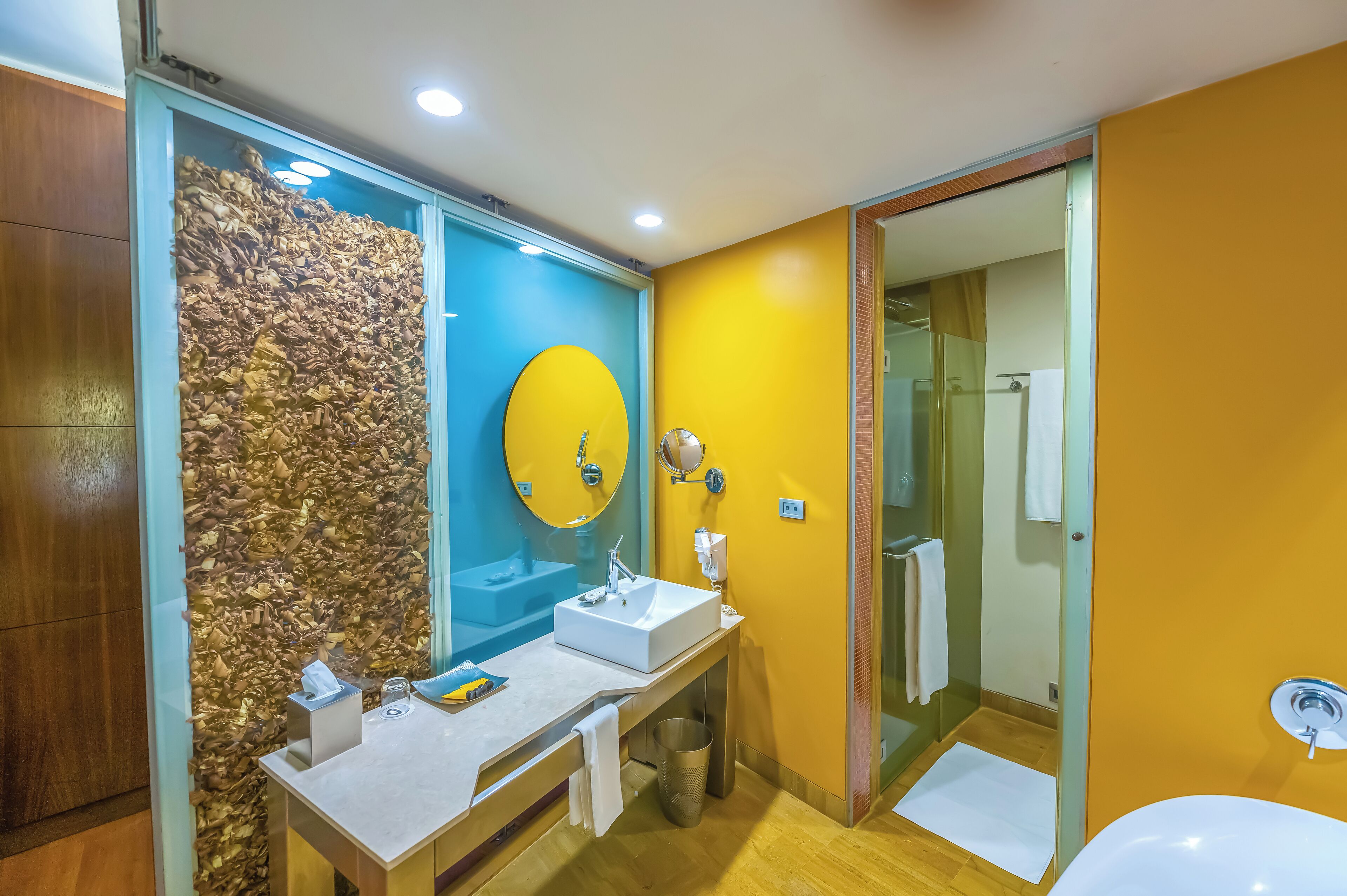 A modern bathroom with a large mirror, two sinks, and a wooden wall feature.