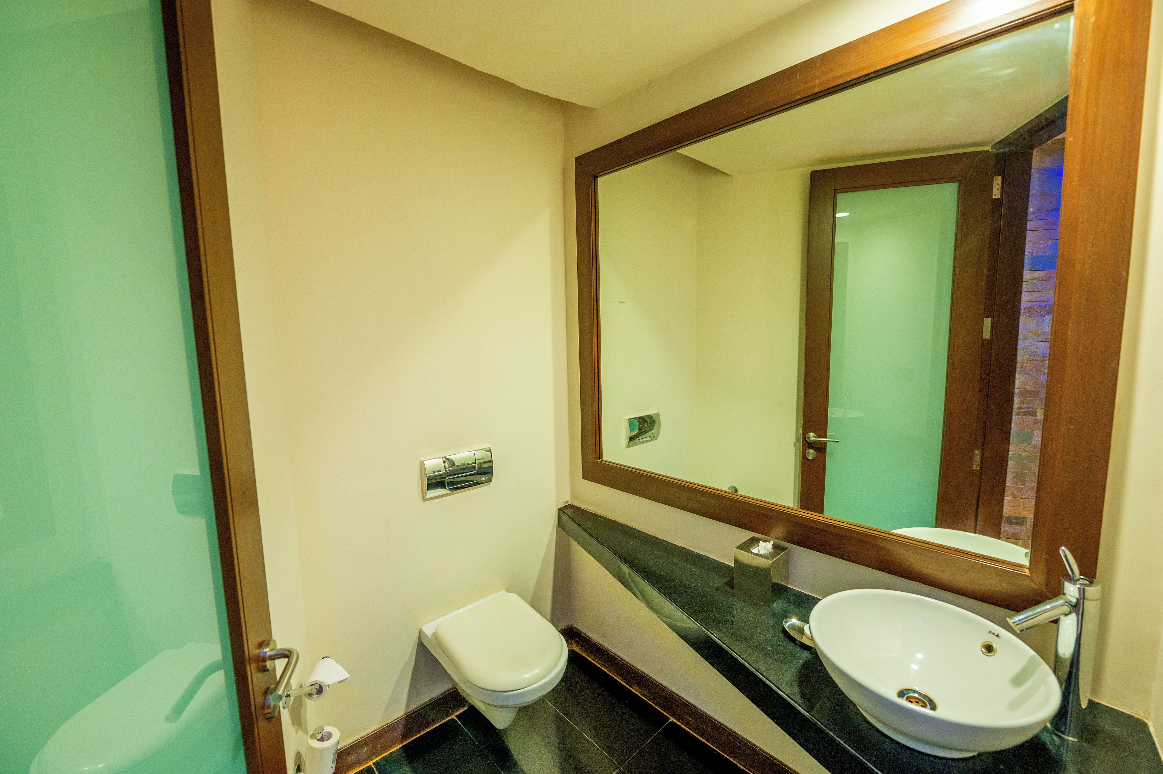 Un baño con inodoro, lavamanos y espejo.