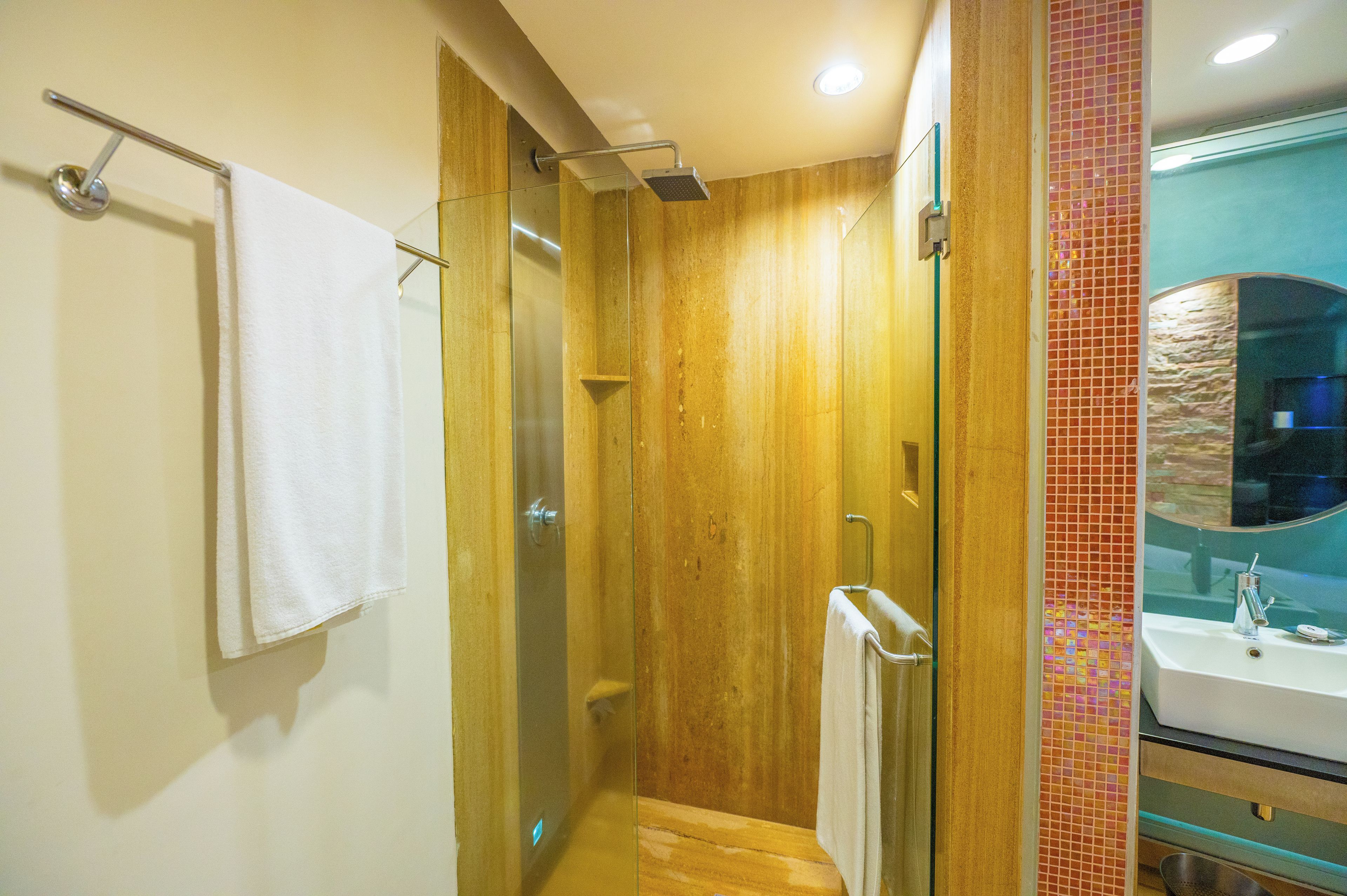 A bathroom with a glass shower enclosure, a towel rack, and a sink with a mirror.