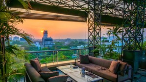 Ein Balkon mit einer Couch, einem Couchtisch und Topfpflanzen.