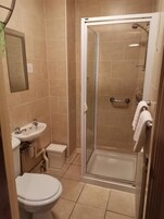 Un baño con inodoro, lavamanos y cabina de ducha con paredes de vidrio.