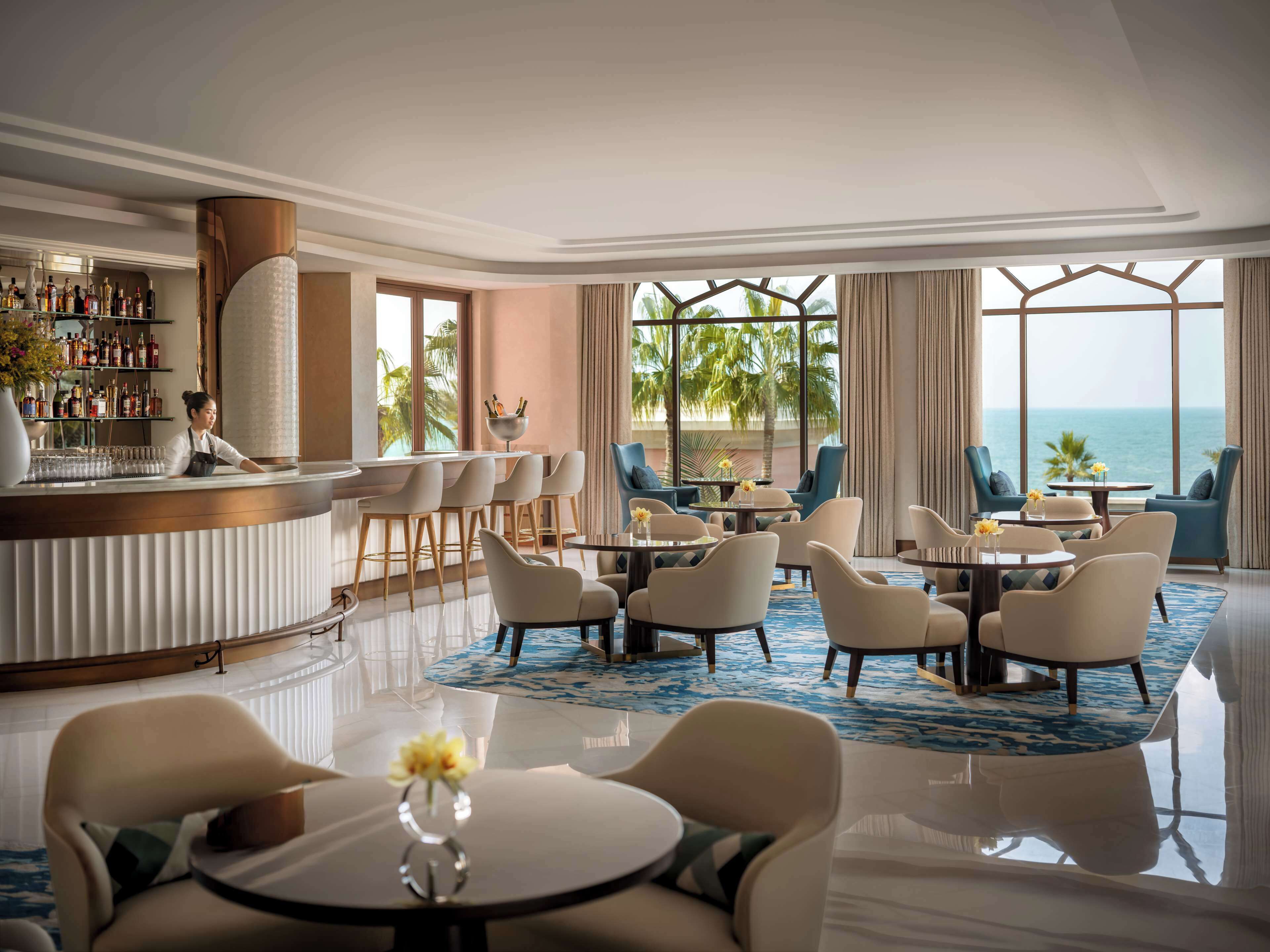 A hotel lobby with a bar, seating area, and large windows overlooking the ocean.