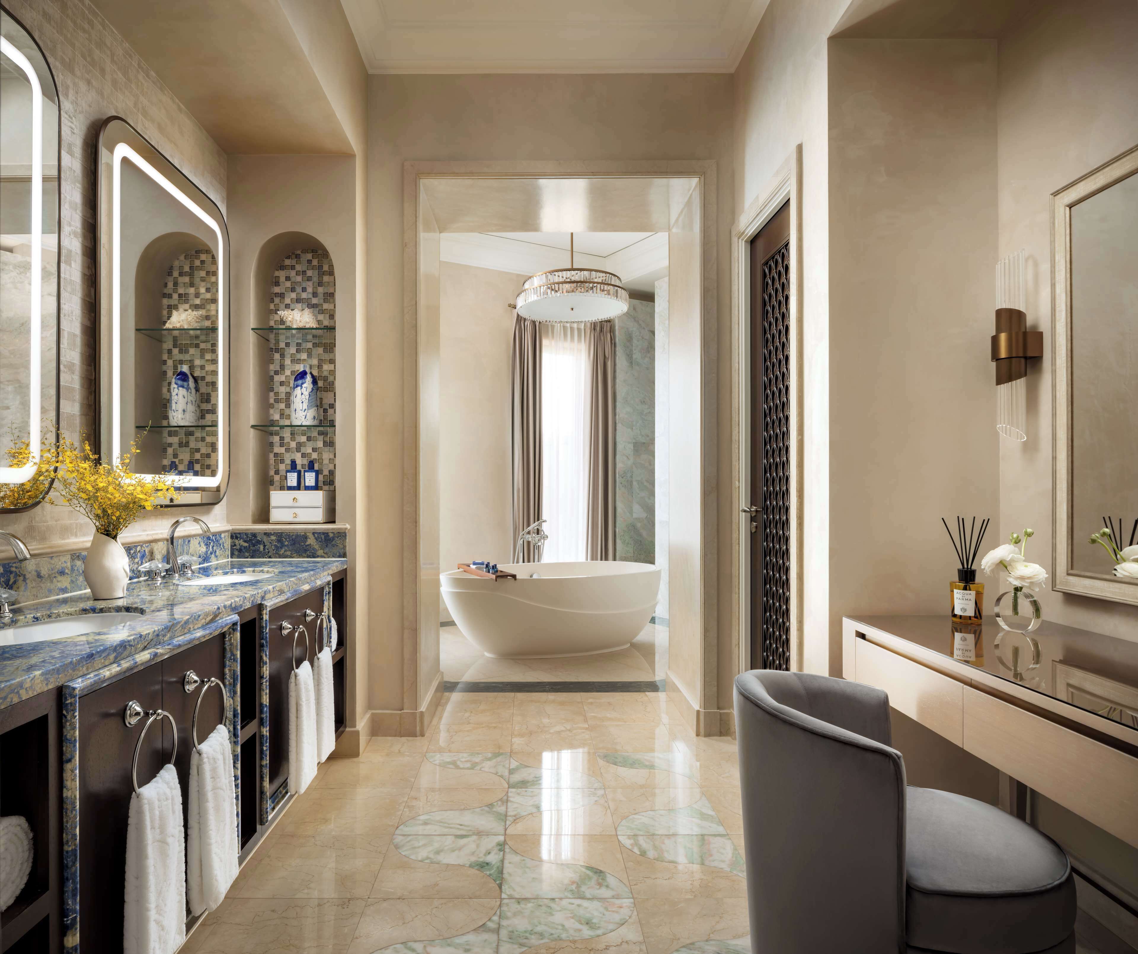 A modern bathroom with a freestanding bathtub, marble countertops, and a large mirror.