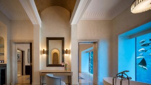 A modern bathroom with a bathtub, a large mirror, and a wall-mounted aquarium.