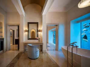 A modern bathroom with a bathtub, a large mirror, and a wall-mounted aquarium.