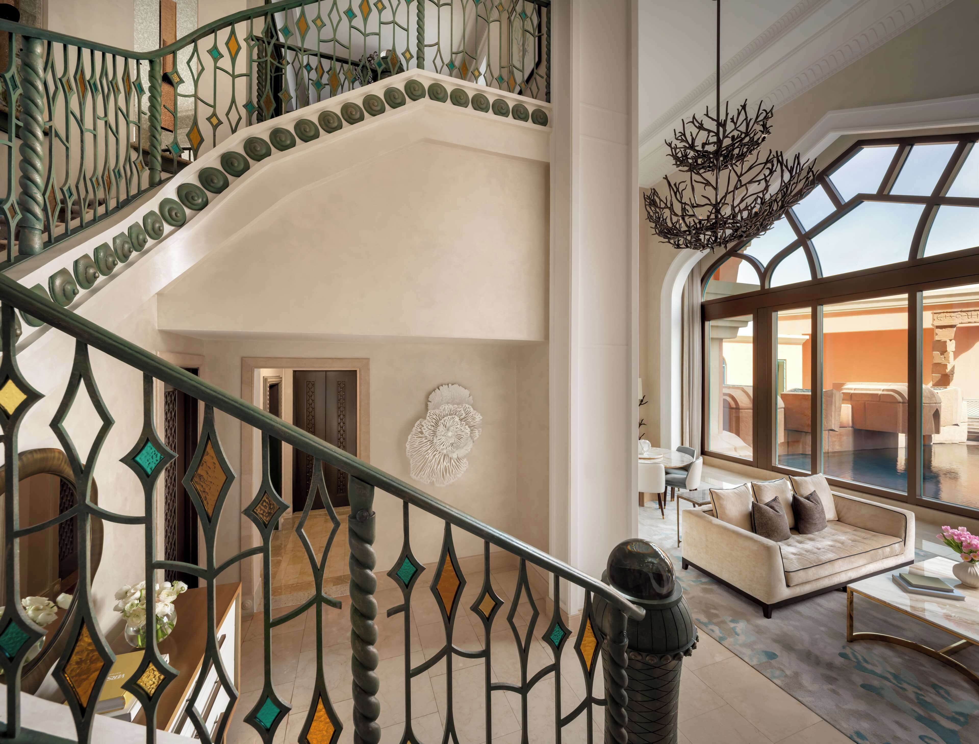 Un interior espacioso con una imponente escalera, una lámpara moderna y un área de descanso con vistas.