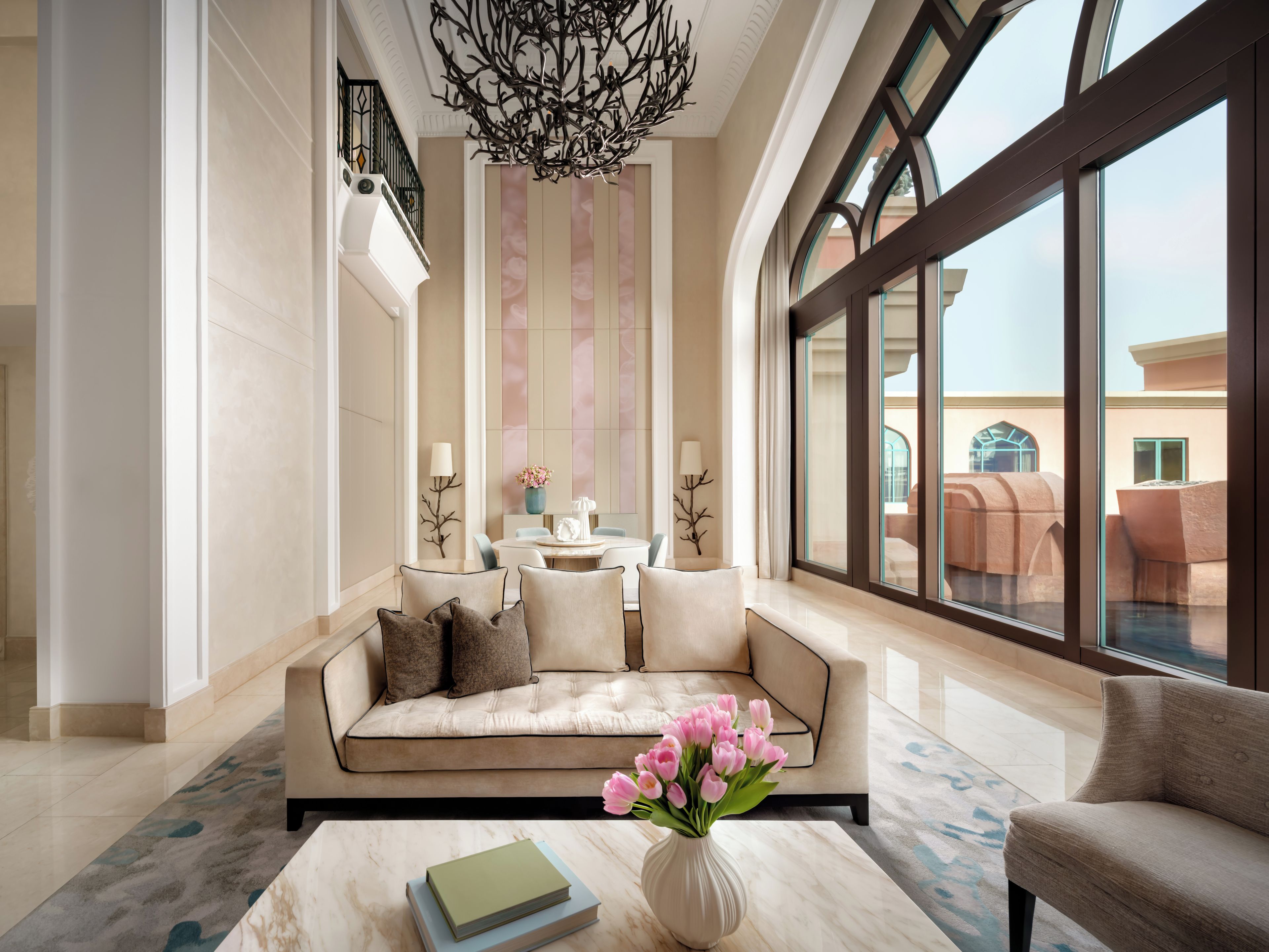 A spacious living area with a large sofa, a coffee table with books, and a vase of flowers.