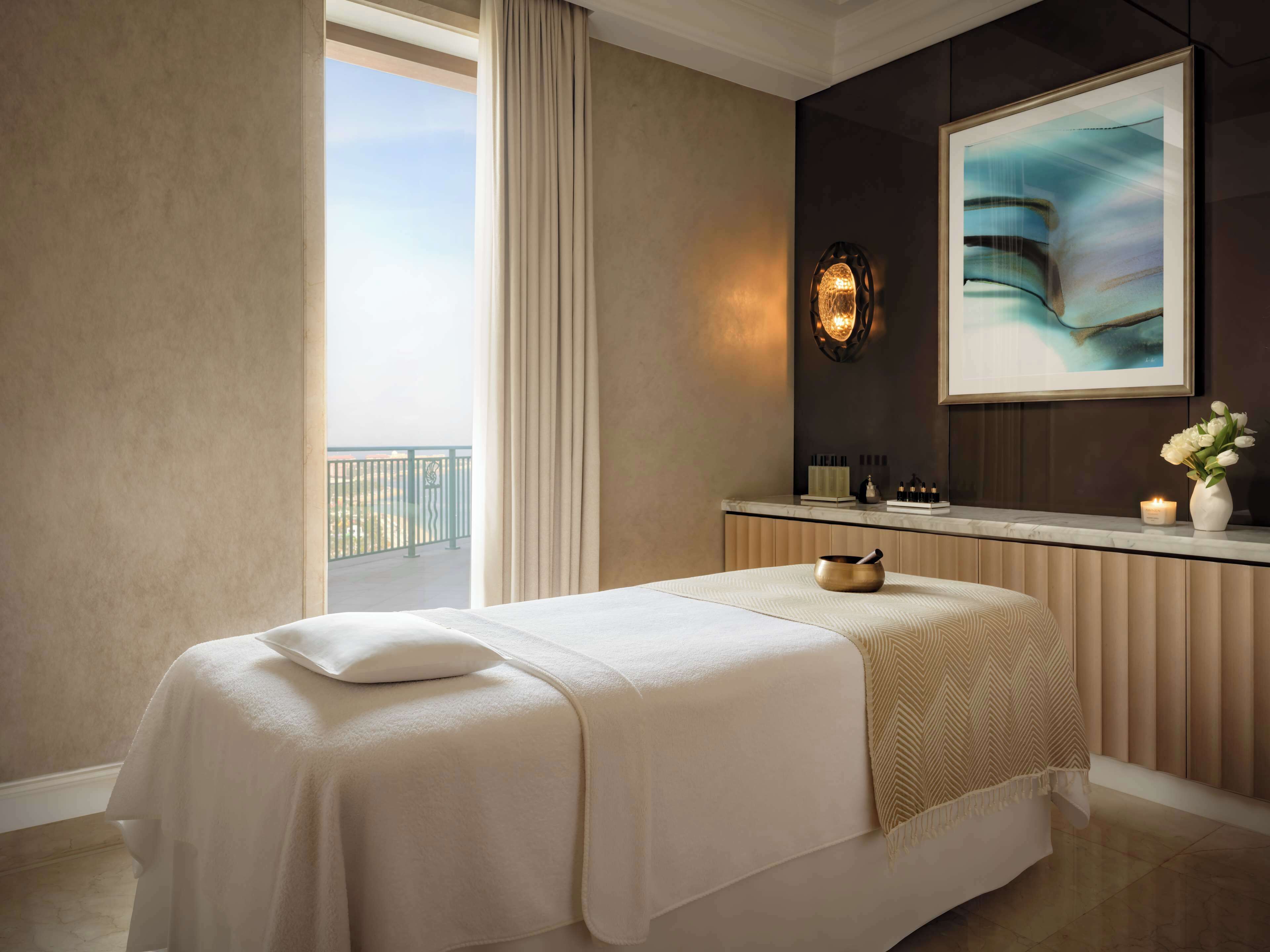 A hotel room with a bed, a bathroom vanity, a framed artwork, and a view of the outdoors.