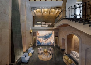 A spacious lobby with a high ceiling, a grand staircase, and a large abstract mural on the wall.