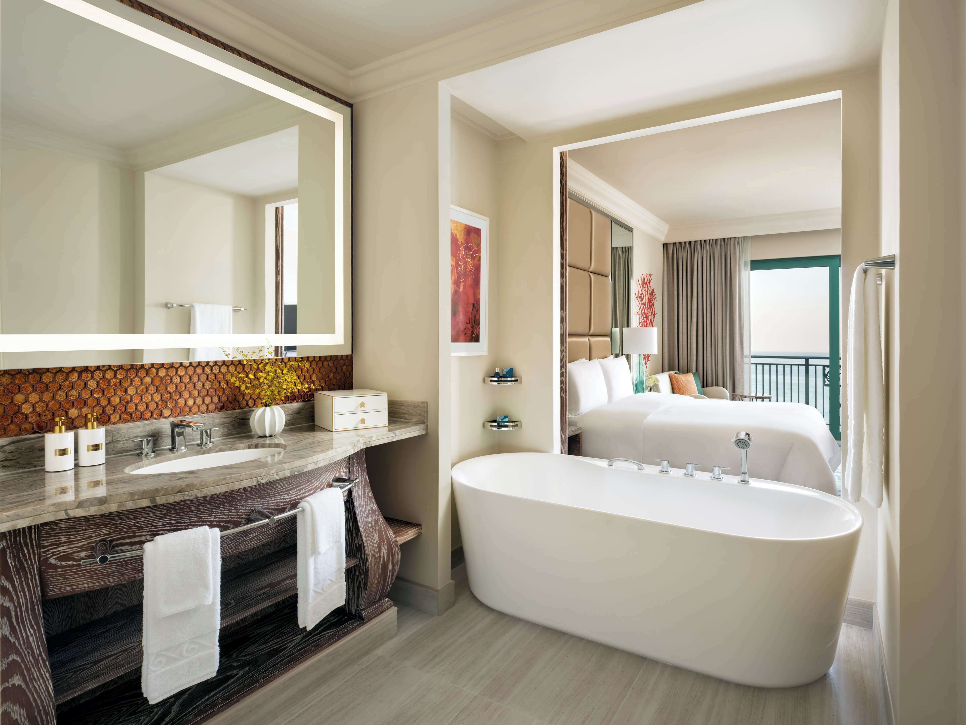 A modern bathroom with a large mirror, a freestanding bathtub, and a vanity with a wooden backsplash.