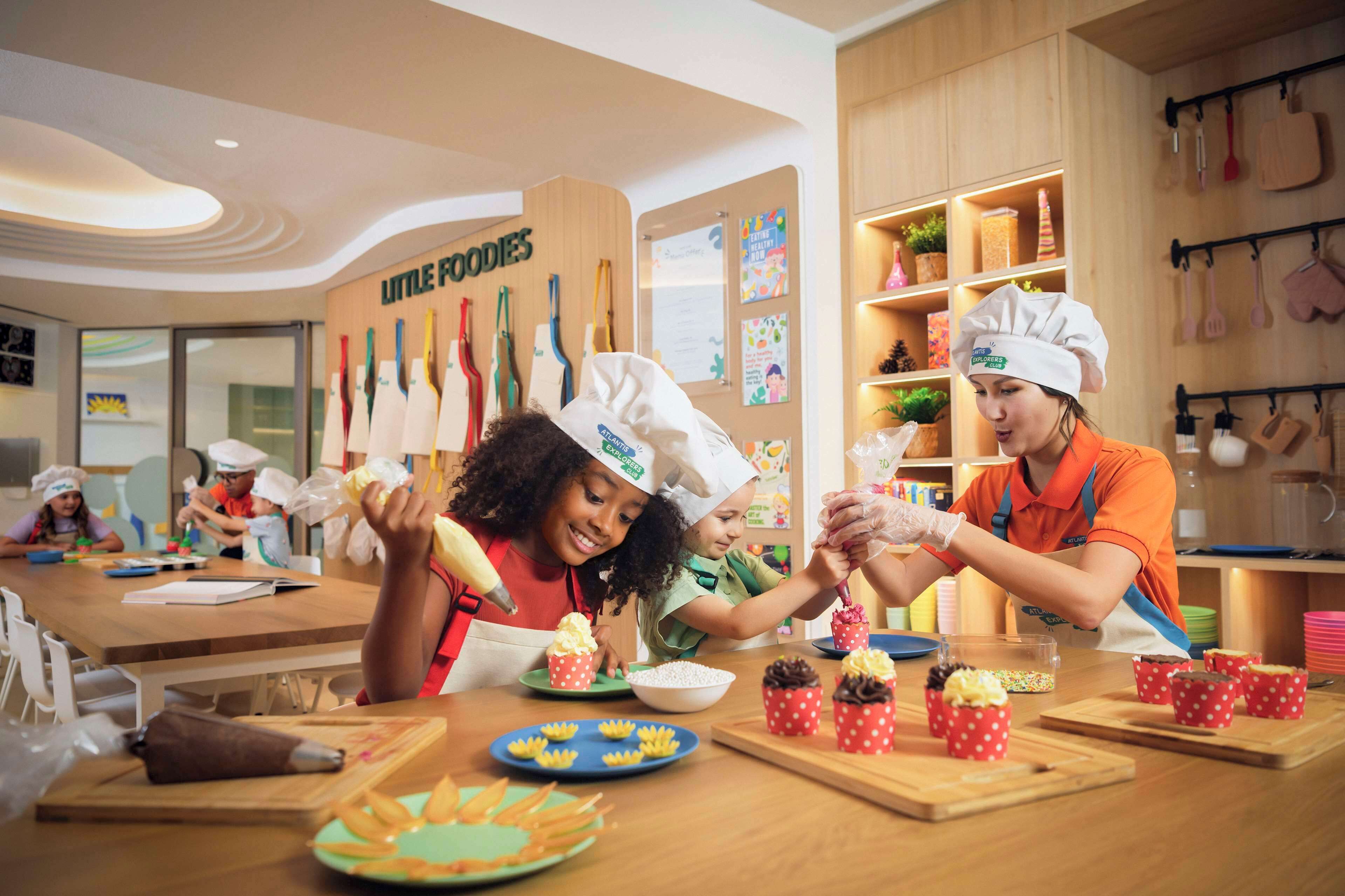 A kitchen area with children and adults wearing chef hats, engaged in cooking activities.
