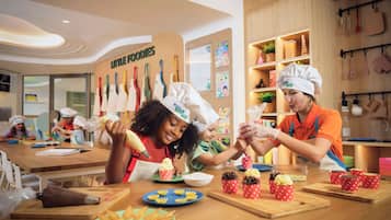 A kitchen area with children and adults wearing chef hats, engaged in cooking activities.