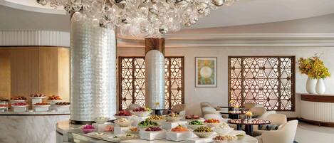 A luxurious hotel lobby with a marble reception desk, a decorative chandelier, and a seating area with sofas.