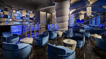 Zona de bar moderna con diversas opciones de asientos, una barra y una estructura espiral única.