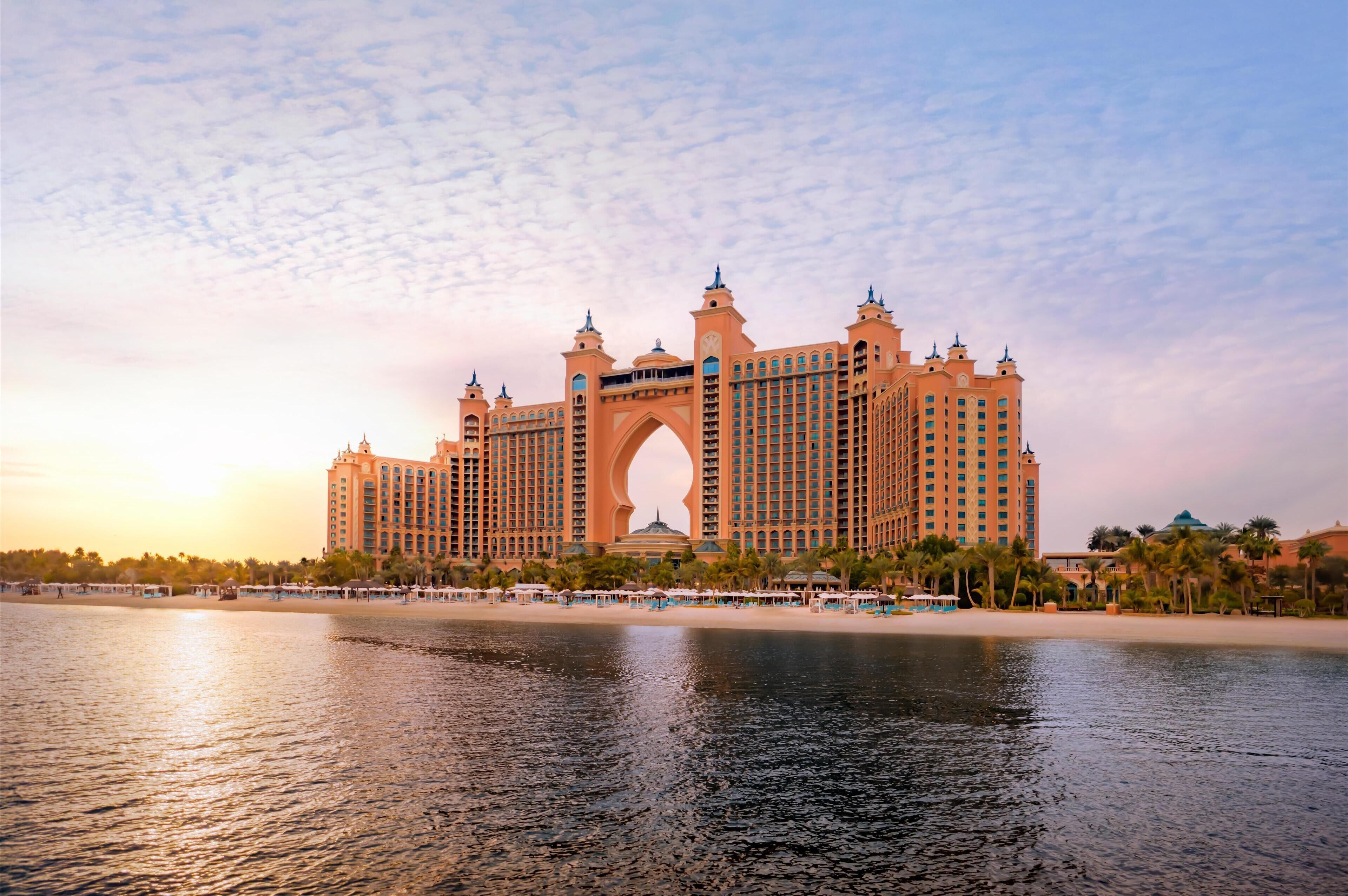 A large hotel with a prominent archway, multiple floors, and a waterfront view.