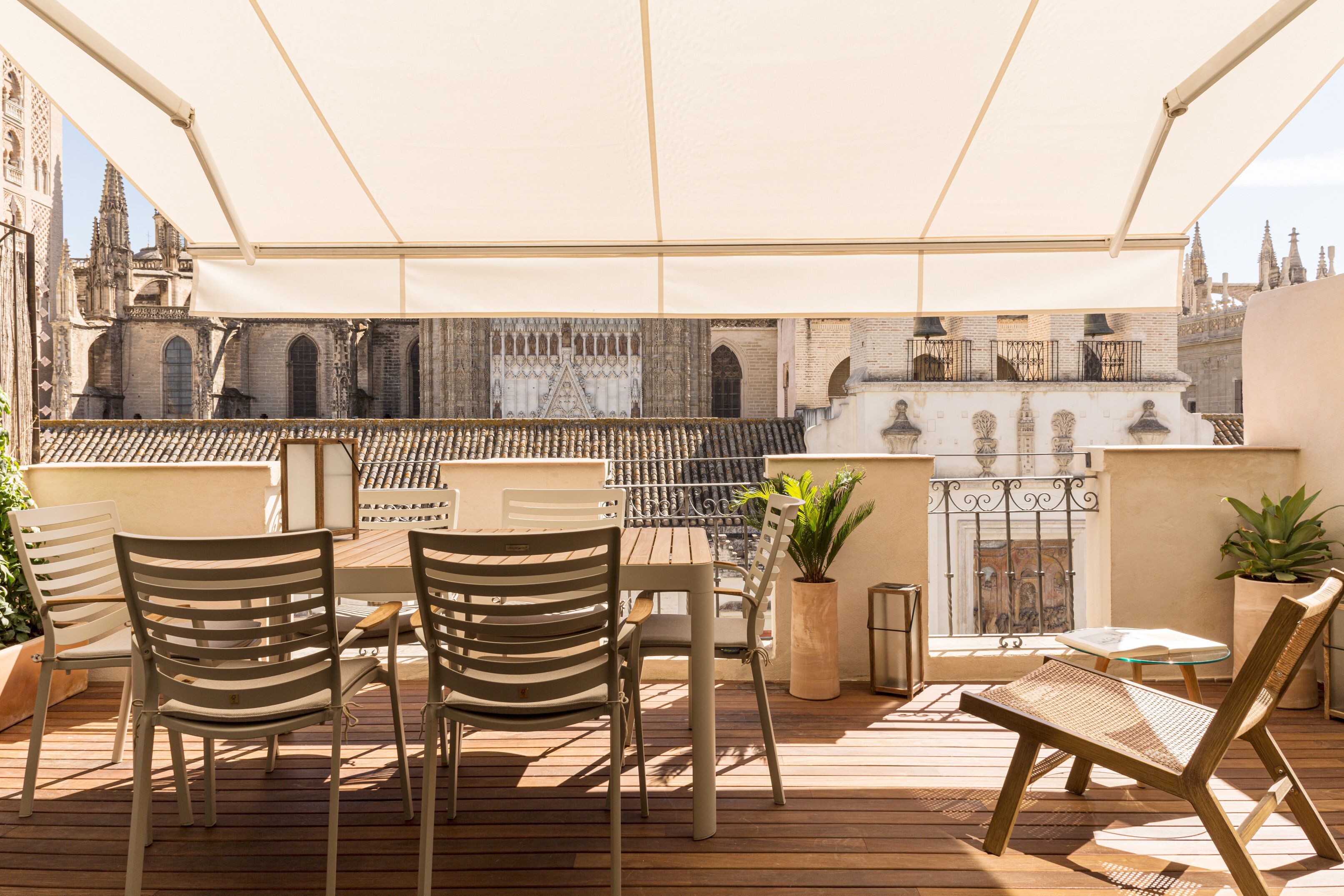 An outdoor terrace with a table and chairs, a potted plant, and a view of historic architecture.