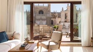 A balcony with a view of a historic cathedral, furnished with a sofa, chairs, and a table with candles. - Puerta Catedral Apartments (Seville)