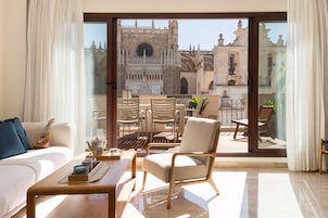 A balcony with a view of a historic cathedral, furnished with a sofa, chairs, and a table with candles.