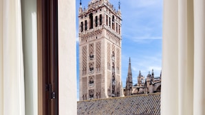 A balcony with a view of a historic tower and surrounding buildings. - Puerta Catedral Apartments (Seville)