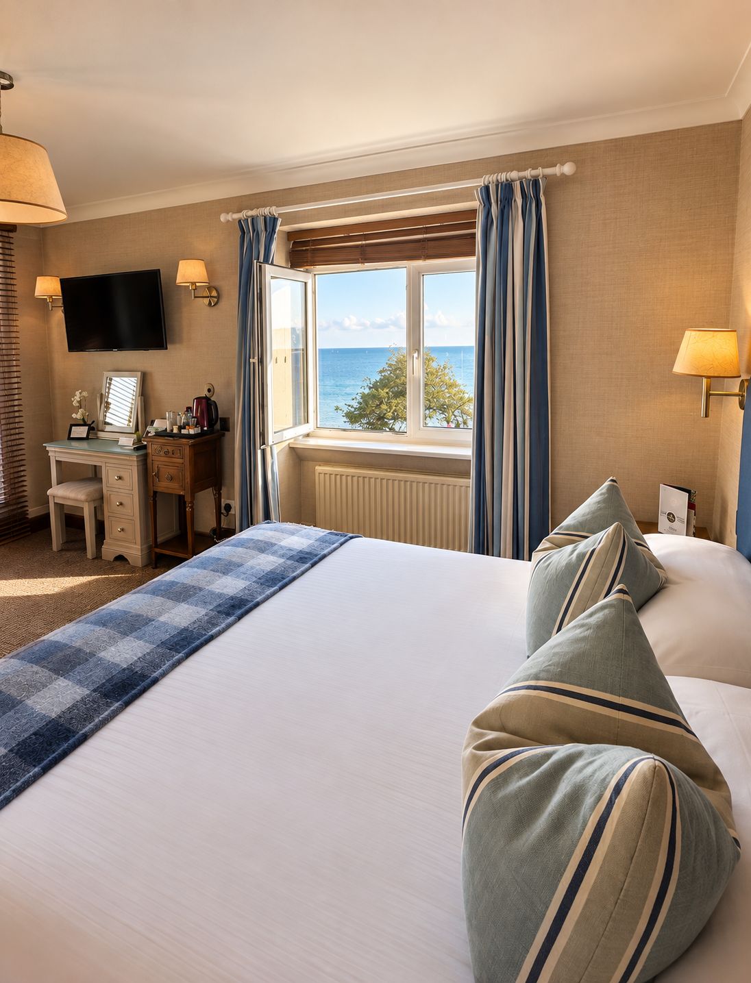 Une chambre d’hôtel avec un lit, un bureau, une télévision et une fenêtre avec des rideaux.