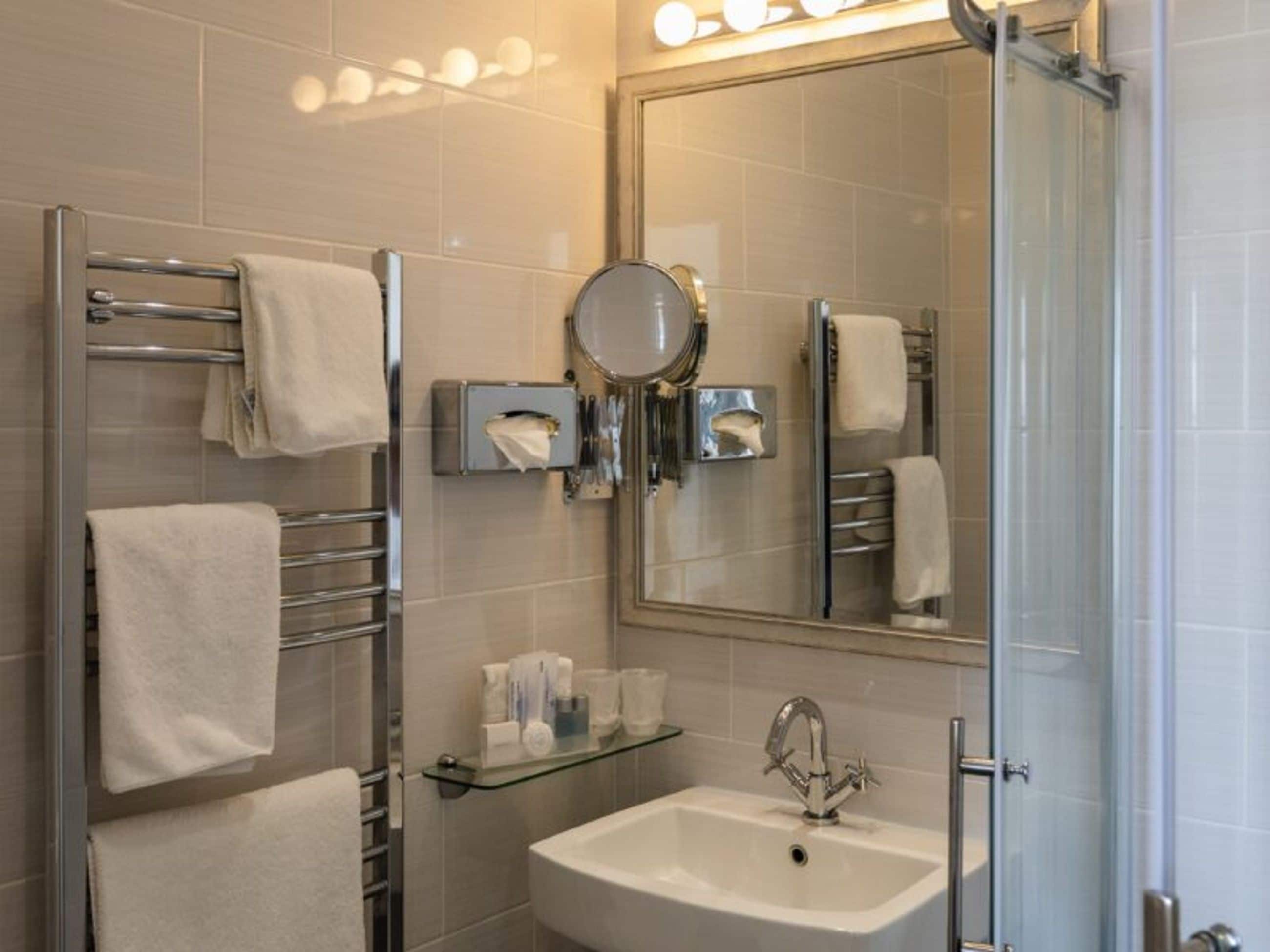 A modern bathroom with a glass shower enclosure, a sink with a chrome faucet, and a mirror above the sink.