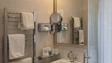 A modern bathroom with a glass shower enclosure, a sink with a chrome faucet, and a mirror above the sink.