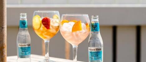 Three glasses of beverages with bottles of Fever Tree Mediterranean Tonic Water.