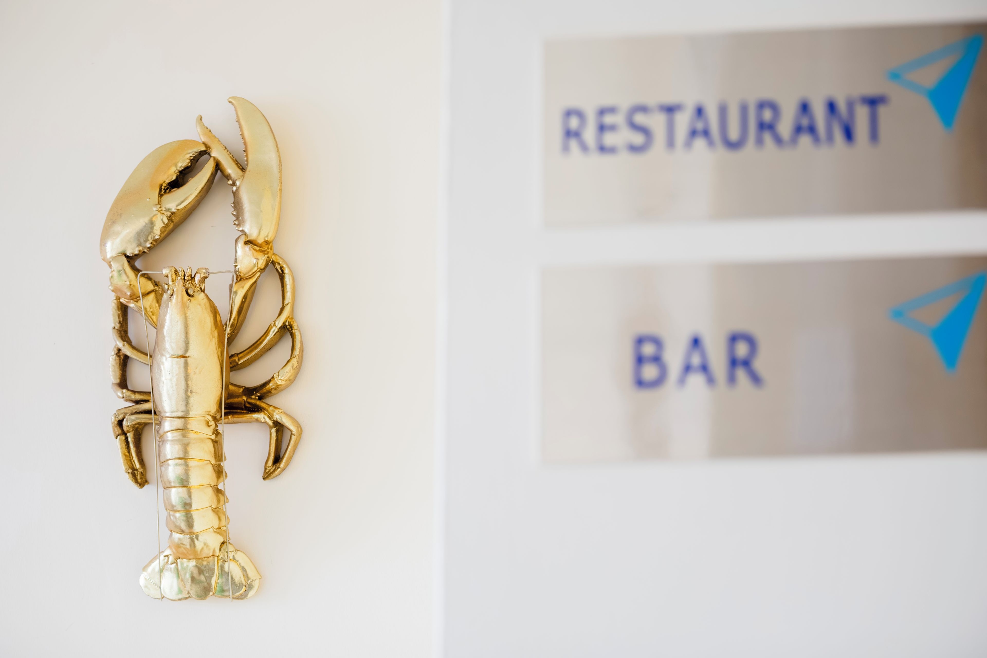 A gold lobster decoration and signs for a restaurant and bar.