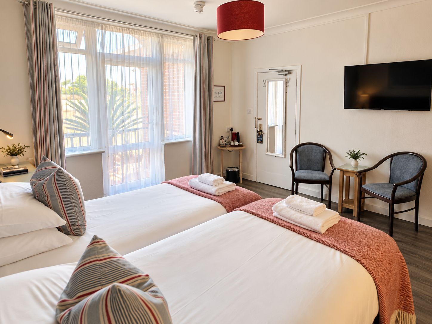Een hotelkamer met twee bedden, een televisie en een klein tafeltje met stoelen.