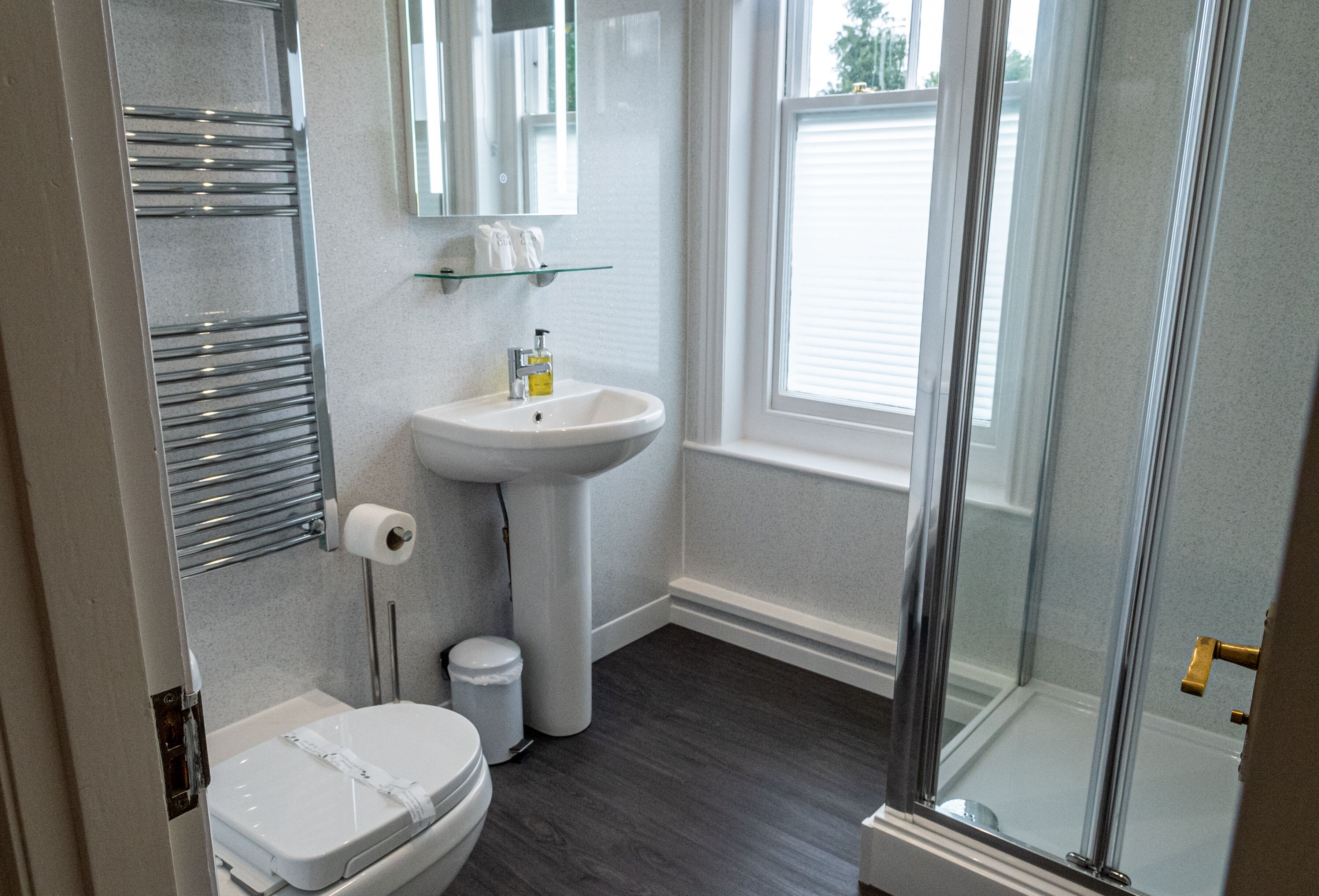 A bathroom with a toilet, sink, and glass shower enclosure.