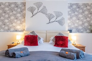 Quarto de hotel com uma cama, duas mesas de cabeceira, luminárias e arte decorativa na parede.