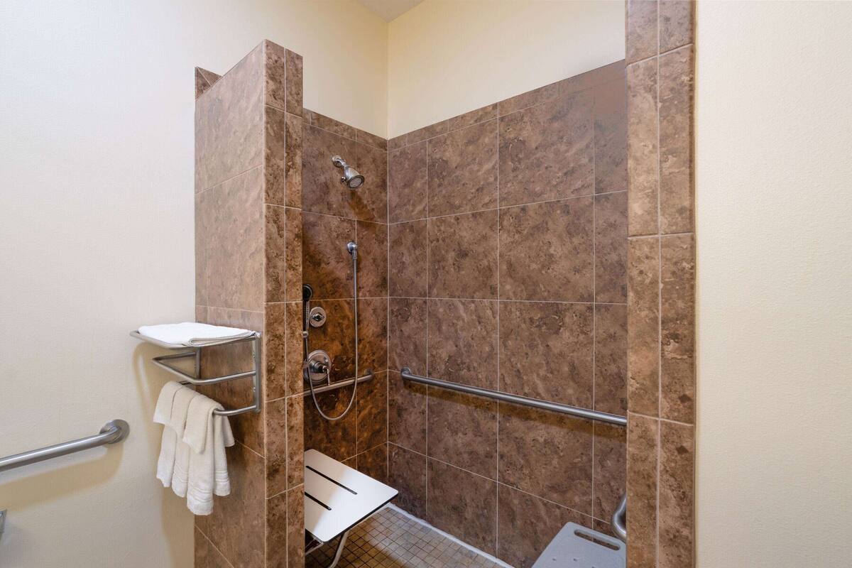 Un espacio de ducha con barra de apoyo, toallero y ducha.