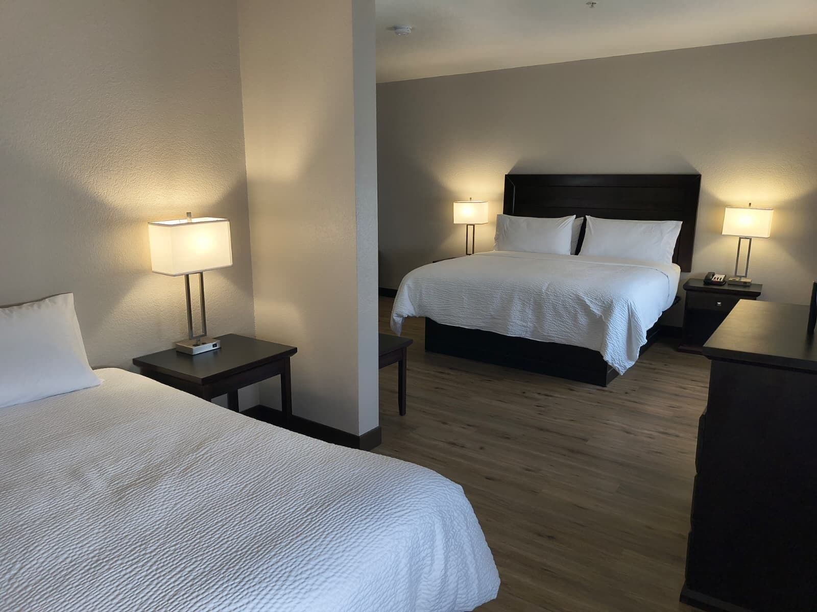 Une chambre d’hôtel avec deux lits, un plancher en bois et des lampes de chevet.
