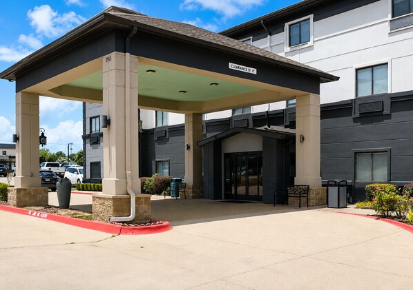 A hotel entrance with a covered waiting area, a clear sign indicating a 13' clearance, and a parking lot with a red curb. - Garner Hotel Tyler Southwest by IHG (Tyler)