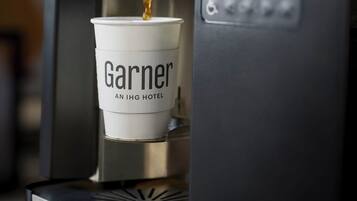 Eine Kaffeemaschine füllt Kaffee in eine Tasse, die mit 'Garner AN IHG HOTEL' beschriftet ist.