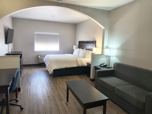 A hotel room with a bed, a desk, a chair, a sofa, and a TV. - Garner Hotel Tyler Southwest by IHG (Tyler)