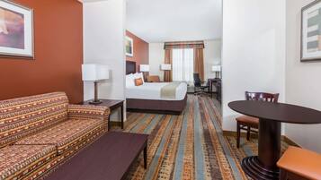 A hotel room with a sofa, a bed, a dining table, and a chair.