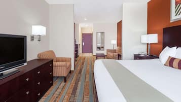 Una habitación de hotel con una cama grande, televisión, escritorio con lámpara y una silla.