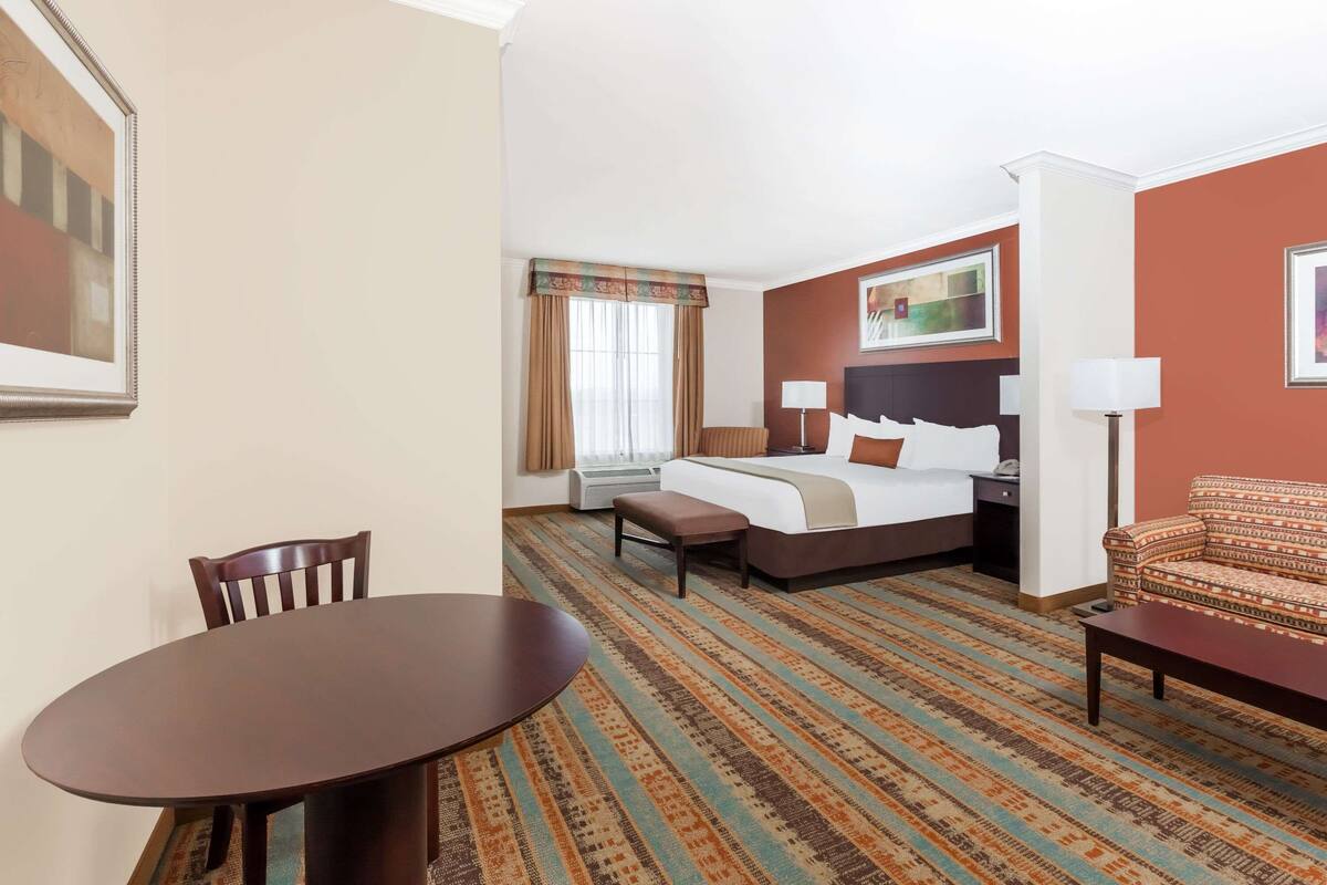 A hotel room with a bed, a desk, a chair, and a dining table.