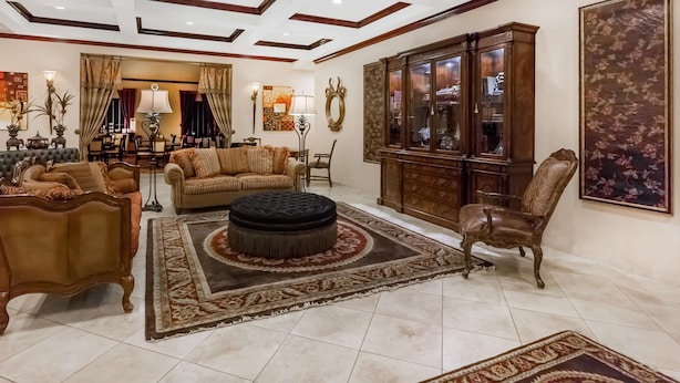 A spacious living room with a large wooden cabinet, a sofa set, and a patterned rug. - Baymont by Wyndham Henderson (Henderson)