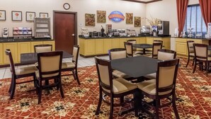 A breakfast area with a counter, seating, and a clock on the wall. - Baymont by Wyndham Henderson (Henderson)