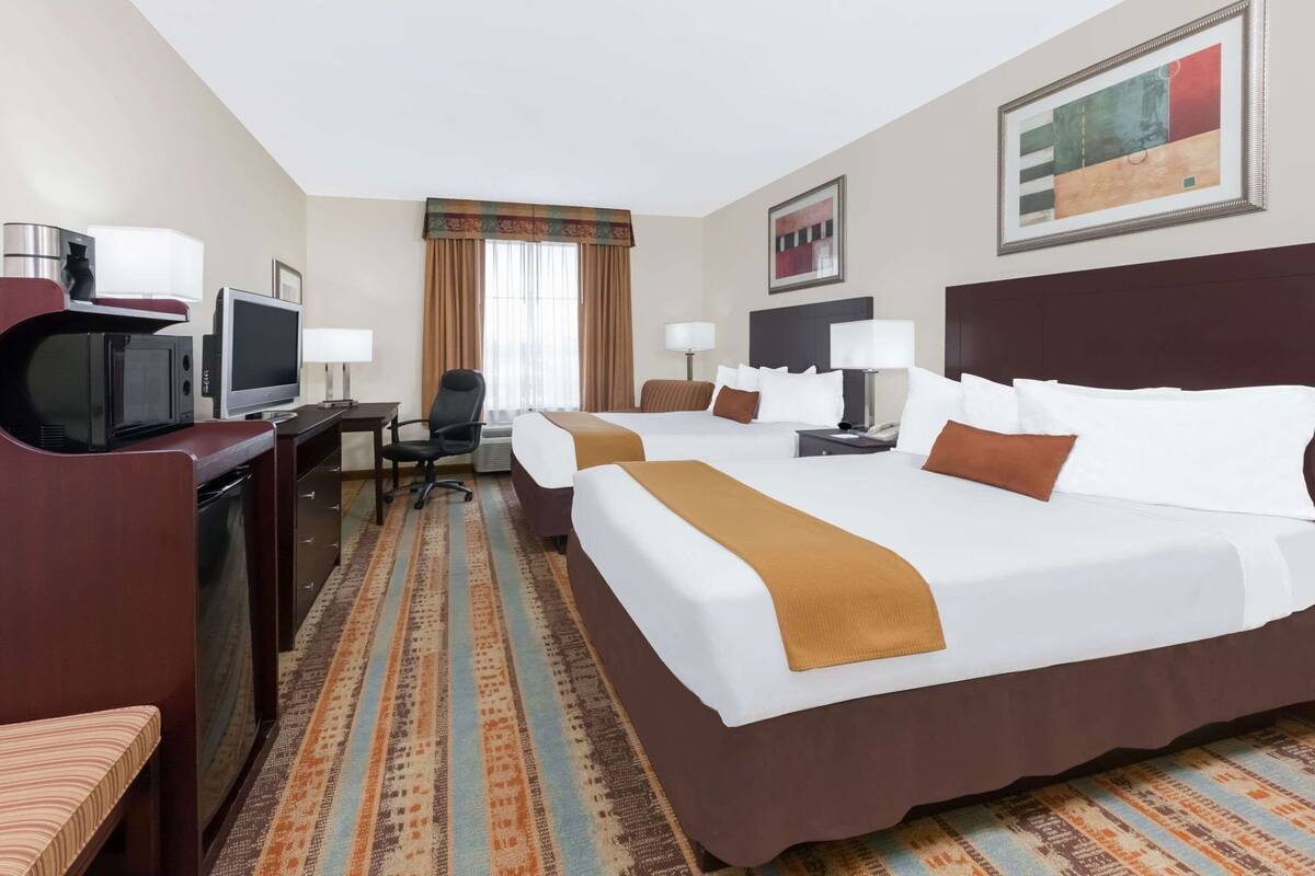 A hotel room with a large bed, a desk with a computer, a chair, and a television.