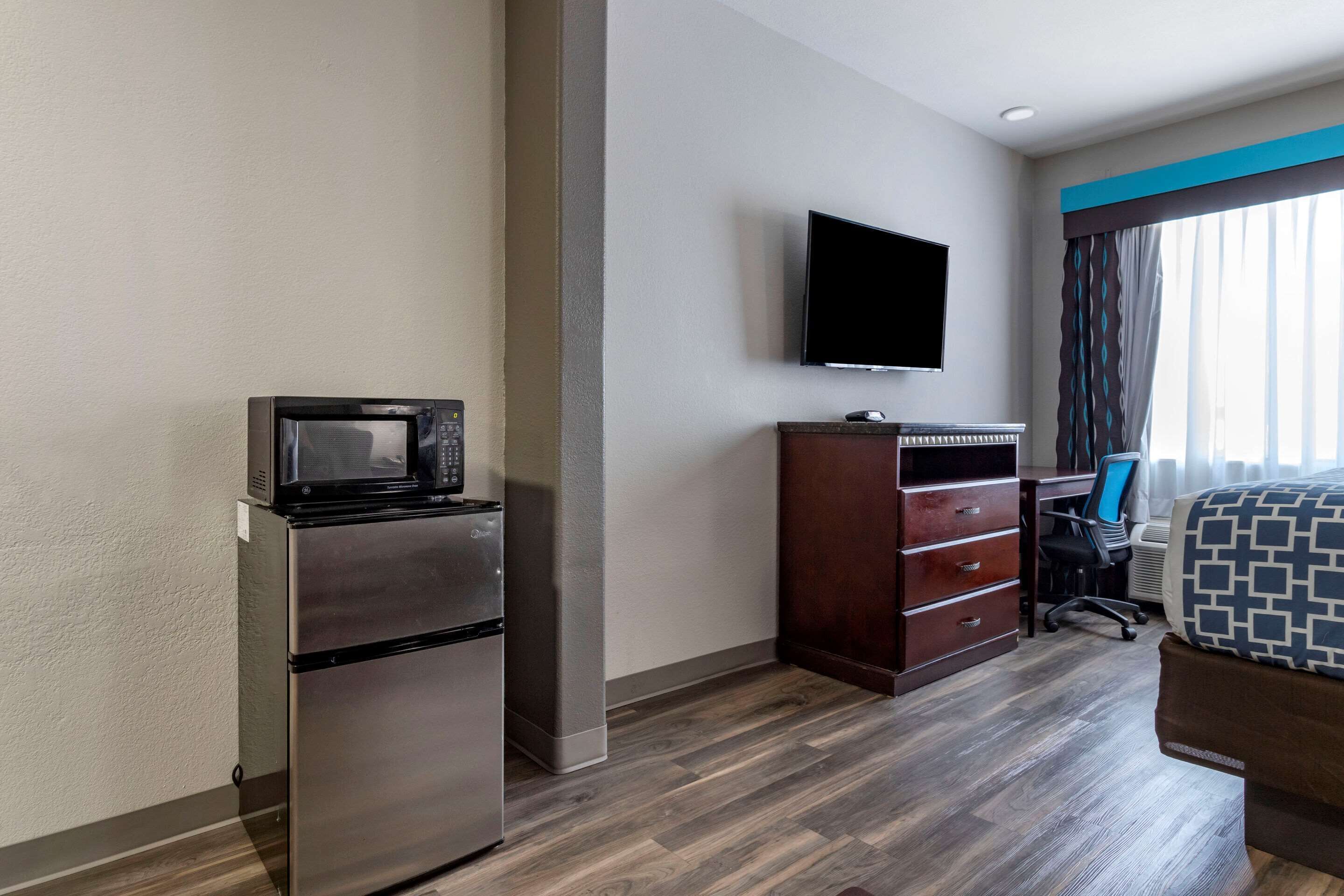 Une chambre d’hôtel équipée d’une kitchenette, d’un téléviseur à écran plat, d’un bureau avec une chaise et d’un lit.