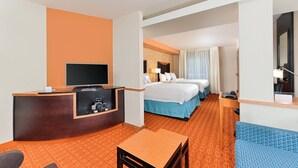 Une chambre d’hôtel équipée d’un bureau, d’une télévision, de deux lits, d’un canapé et d’une moquette à motifs.