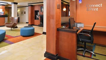 Um hall de hotel com balcão de recepção, computador e áreas de estar.